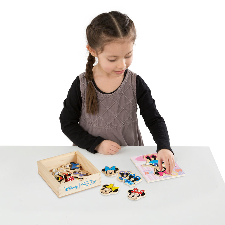 A child on white background with The Melissa & Doug Disney Minnie Mouse Mix and Match Dress-Up Wooden Play Set Puzzle (18 pcs)