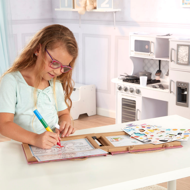 A kid playing with The Melissa & Doug Natural Play: Play, Draw, Create Reusable Drawing & Magnet Kit – Princesses (54 Magnets, 5 Dry-Erase Markers)