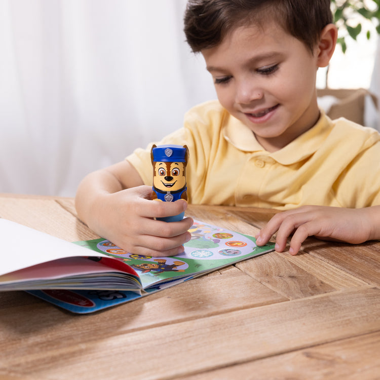 A kid playing with The Melissa & Doug Sticker WOW!™ PAW Patrol Chase Bundle: 24-Page Activity Pad, Sticker Stamper, 500 Stickers, Mini Pad, Arts and Crafts Fidget Toy Collectible Character