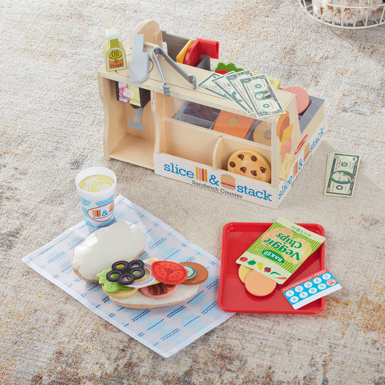 A playroom scene with The Melissa & Doug Wooden Slice & Stack Sandwich Counter with Deli Slicer – 56-Piece Pretend Play Food Pieces