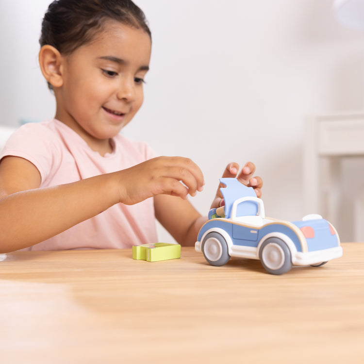 A kid playing with The Melissa & Doug Cheery Lane Vehicle and Boy Figure, Wooden Toy Convertible Car Playset - For Ages 2+