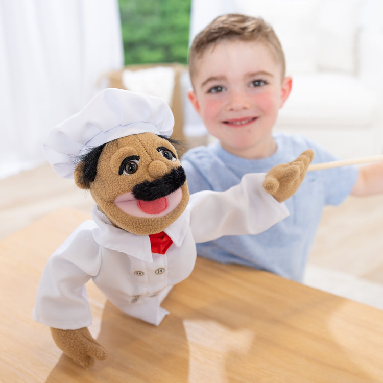 A kid playing with The Melissa & Doug Chef Puppet (Al Dente) with Detachable Wooden Rod