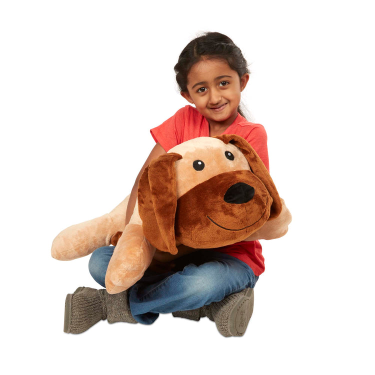 A child on white background with The Melissa & Doug Cuddle Dog Jumbo Plush Stuffed Animal with Activity Card