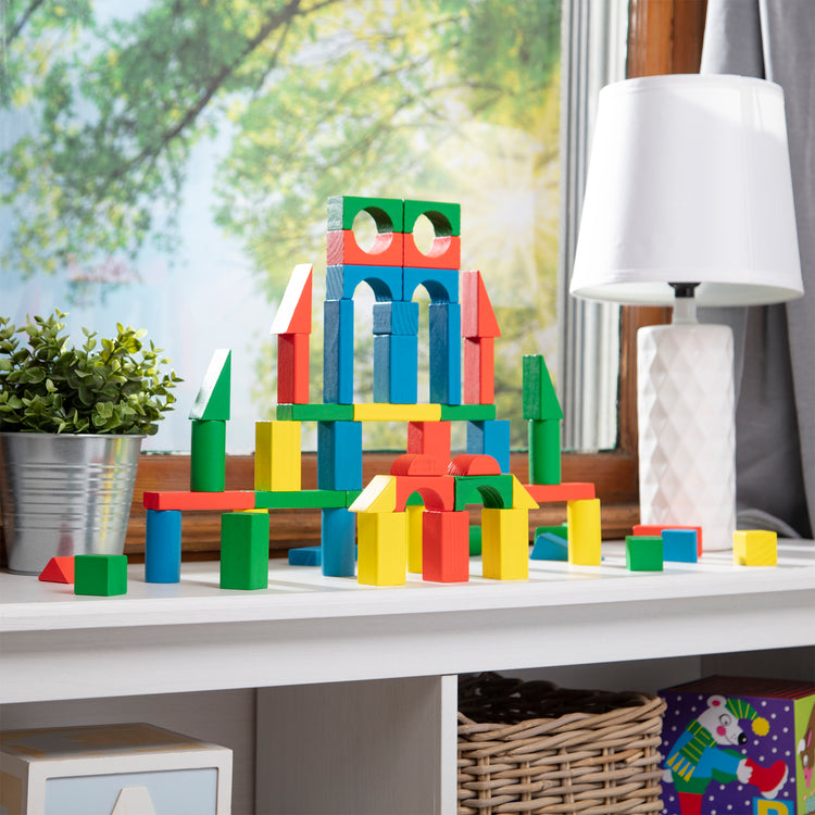 A playroom scene with The Melissa & Doug Wooden Building Blocks Set - 100 Blocks in 4 Colors and 9 Shapes