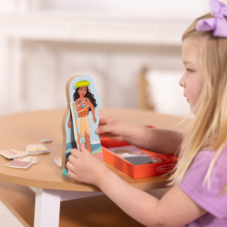 A kid playing with The Melissa & Doug Disney Princess Moana Magnetic Dress-Up Wooden Doll Pretend Play Set (30+ pcs)

