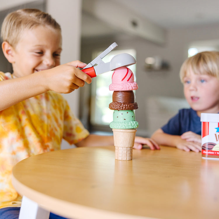 A kid playing with The Melissa & Doug Scoop and Stack Ice Cream Cone Magnetic Pretend Play Set, Multicolor