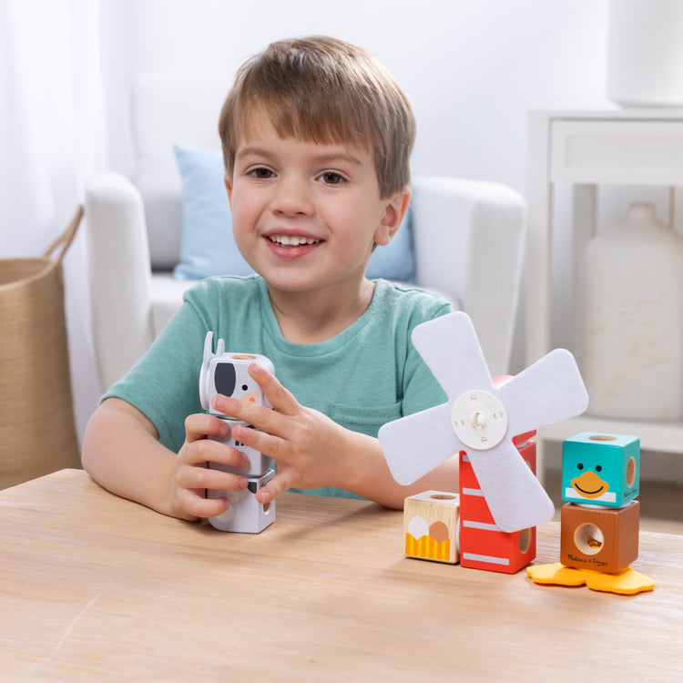 A kid playing with The Melissa & Doug Blockables™ Farm and Woodland 2-Pack Bundle Connectable Wooden Building Blocks Preschool Play Set Toy 