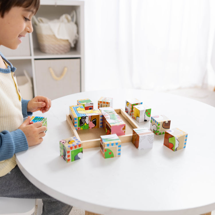 A kid playing with The Melissa & Doug Farm Wooden Cube Puzzle With Storage Tray - 6 Puzzles in 1 (16 pcs)