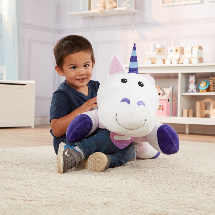 A kid playing with The Melissa & Doug Cuddle Unicorn Jumbo Plush Stuffed Animal with Activity Card