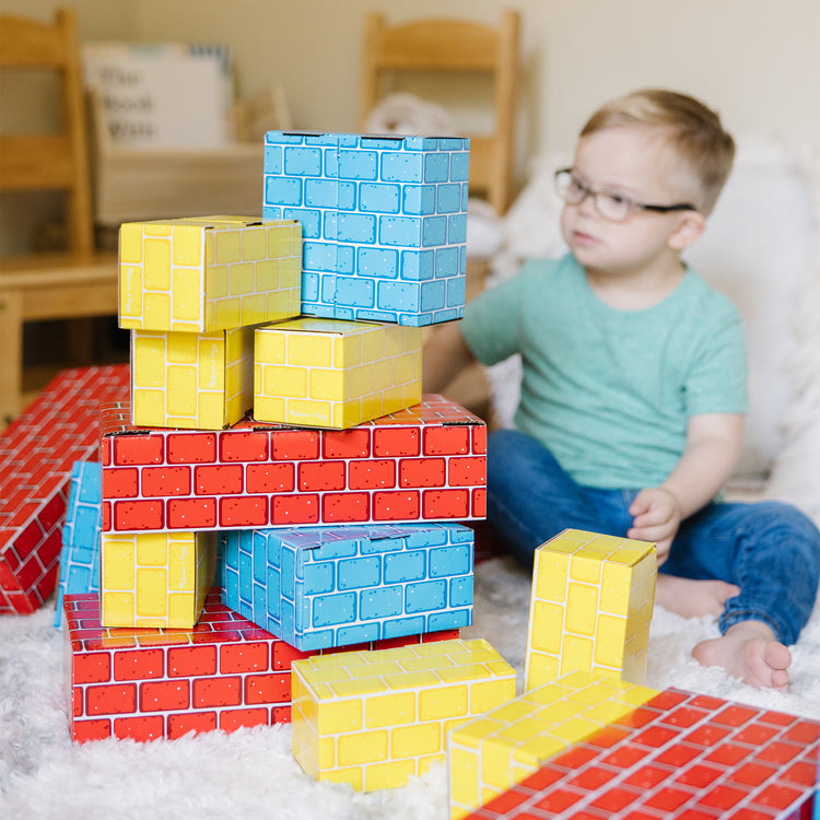 A kid playing with The Melissa & Doug Jumbo Extra-Thick Cardboard Building Blocks - 40 Blocks in 3 Sizes
