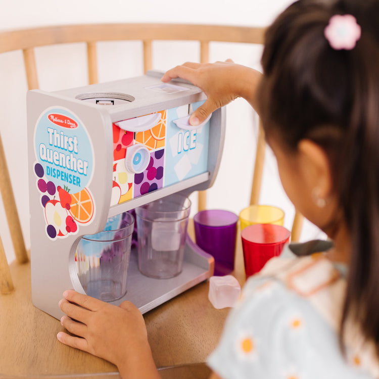 A kid playing with The Melissa & Doug Wooden Thirst Quencher Drink Dispenser With Cups, Juice Inserts, Ice Cubes