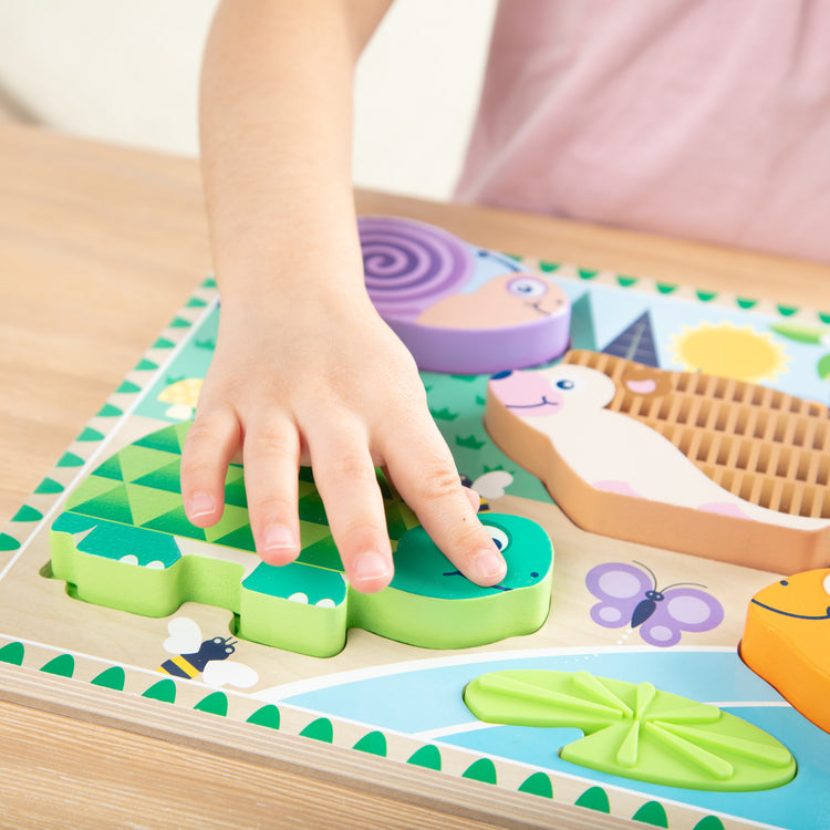 A kid playing with The Forest Friends Touch & Feel Puzzle