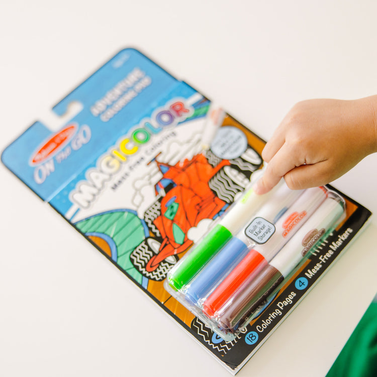 A kid playing with The Melissa & Doug On the Go Magicolor Coloring Pad: Adventure - 18 Coloring Pages and 4 Markers