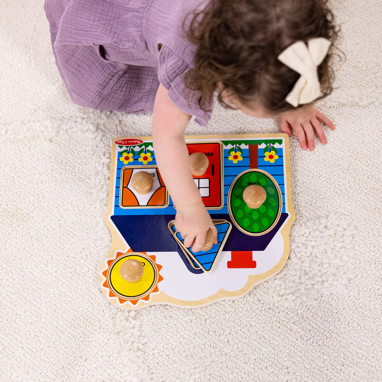 A kid playing with The Melissa & Doug First Shapes Jumbo Knob Wooden Puzzle