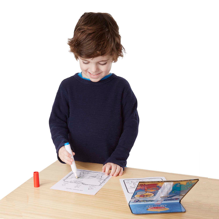 A child on white background with The Melissa & Doug On the Go ColorBlast! Activity Book: Sea Life - 24 Pictures and No-Mess Pen