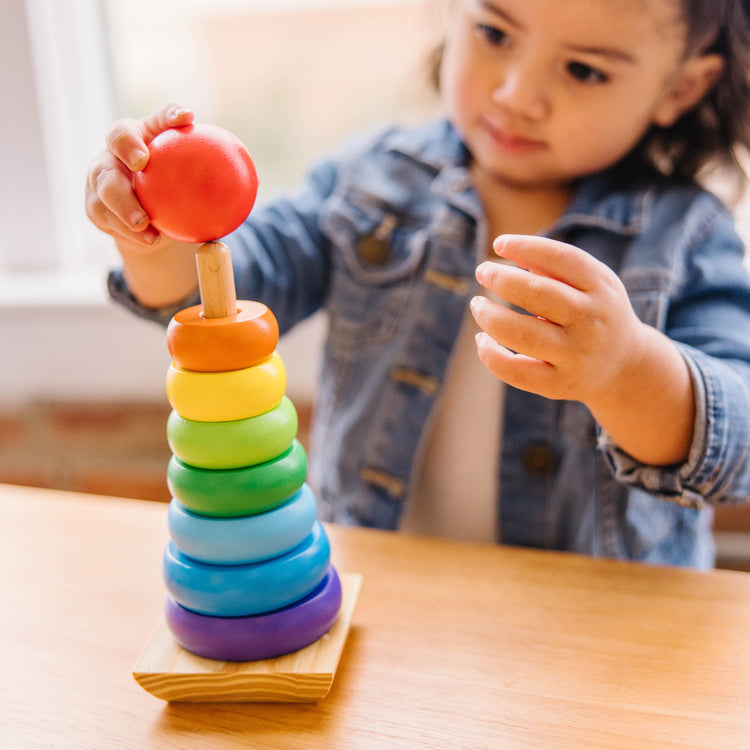 A kid playing with The Melissa & Doug 4 Wooden Classic Rainbow Learning Toys