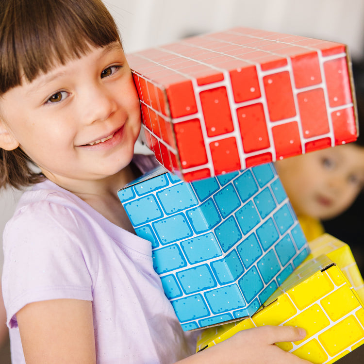 A kid playing with The Melissa & Doug Jumbo Extra-Thick Cardboard Building Blocks - 40 Blocks in 3 Sizes
