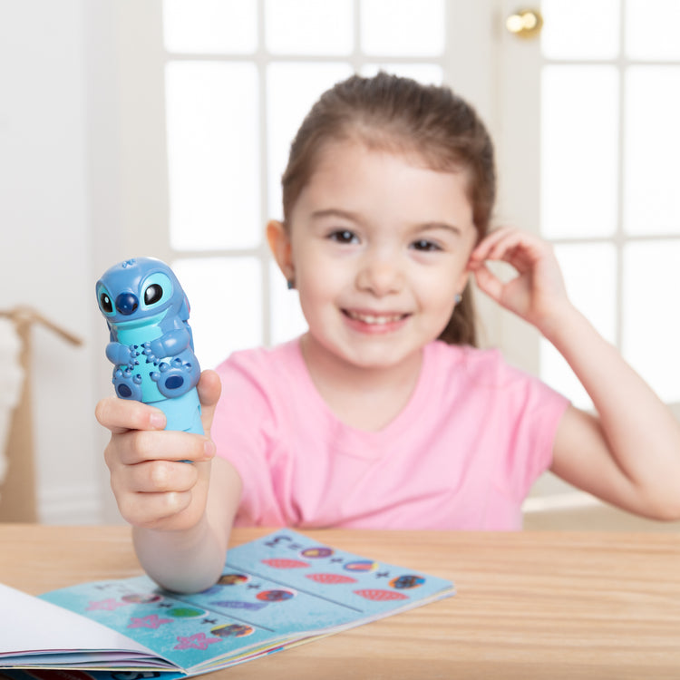 A kid playing with The Melissa & Doug Sticker WOW! Disney Stitch 24-Page Activity Pad with 300 Stickers - For Ages 3+