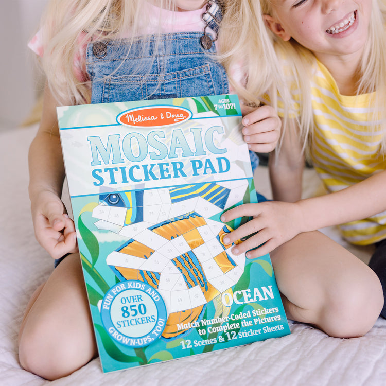 A kid playing with The Melissa & Doug Mosaic Sticker Pad Ocean Animals (12 Color Scenes to Complete with 850+ Stickers)