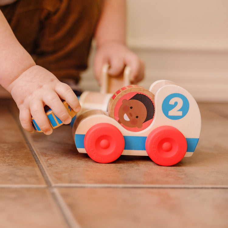 A kid playing with The Melissa & Doug GO Tots Wooden Race Cars (2 Cars, 2 Disks)