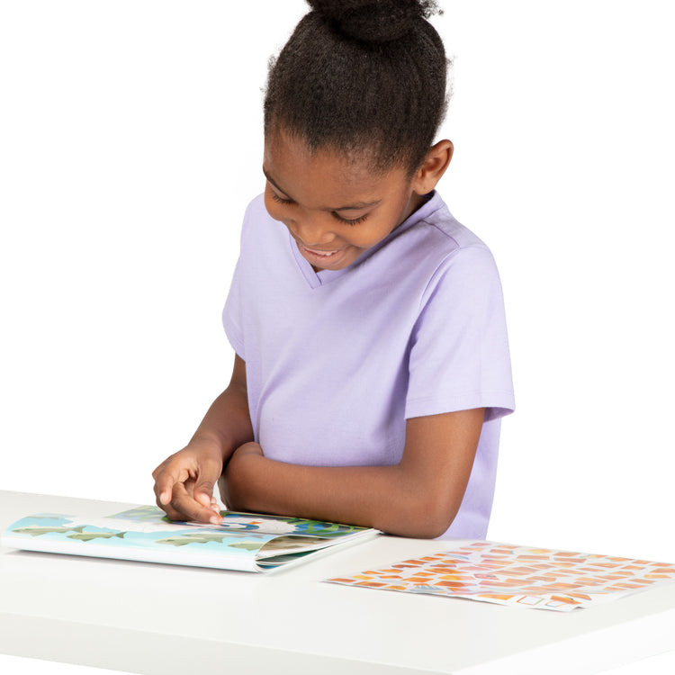 A child on white background with The Melissa & Doug Mosaic Sticker Pad Ocean Animals (12 Color Scenes to Complete with 850+ Stickers)