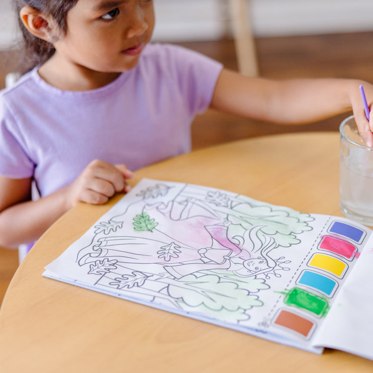 A kid playing with The Melissa & Doug Paint With Water - Princess, 20 Perforated Pages With Spillproof Palettes