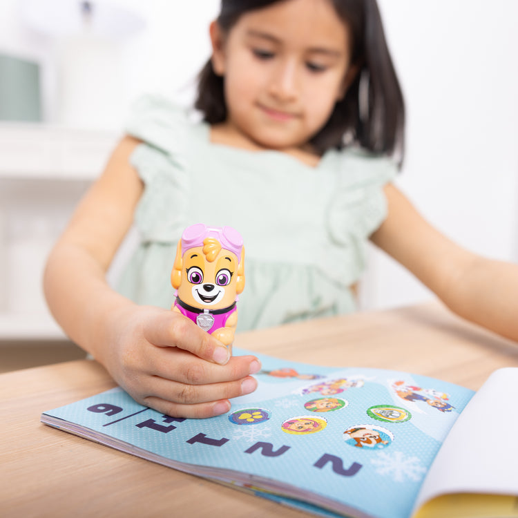 A kid playing with The Melissa & Doug Sticker WOW!™ 24-Page Activity Pad and Sticker Stamper, 300 Stickers, Arts and Crafts Fidget Toy Collectible Character – PAW Patrol Skye
