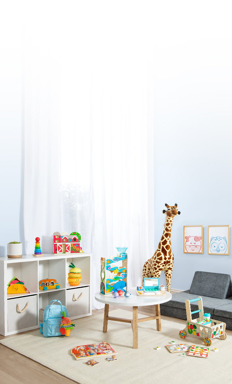 Photo of a baby's playroom with jumbo giraffe stuffed animal, wooden grocery cart, puzzle, and plush baby toys