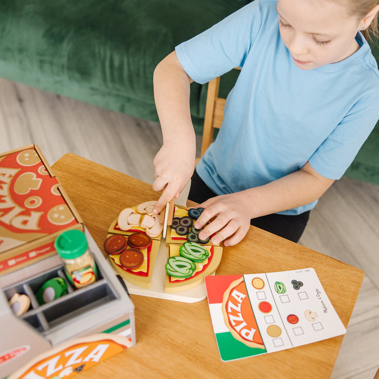 A kid playing with The Melissa & Doug Top & Bake Wooden Pizza Counter Play Set (41 Pcs)