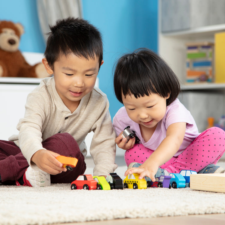 A kid playing with The Melissa & Doug Wooden Cars Vehicle Set in Wooden Tray