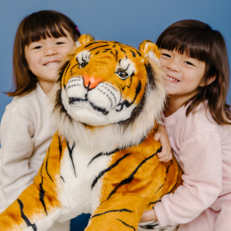 A kid playing with The Melissa & Doug Giant Tiger - Lifelike Stuffed Animal, Over 5 Feet Long (Includes Tail)
