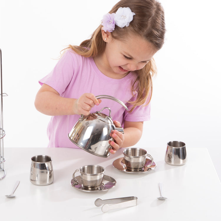 A child on white background with The Melissa & Doug Stainless Steel Pretend Play Tea Set with Storage Rack for Kids (11 pcs)