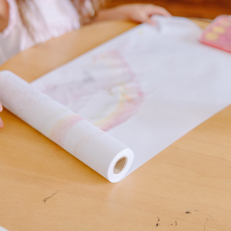 A kid playing with The Melissa & Doug Tabletop Easel Paper Roll (12 inches x 75 feet) - 2-Pack