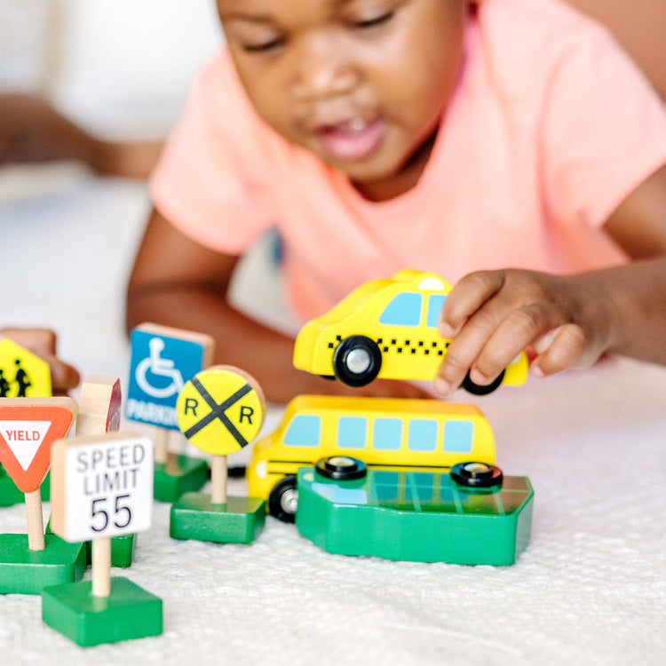 A kid playing with The Melissa & Doug Wooden Vehicles and Traffic Signs With 6 Cars and 9 Signs