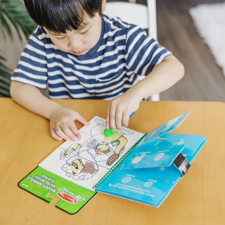 A kid playing with The Melissa & Doug On the Go Water Wow! Reusable Water-Reveal Flip Pad - Wacky Animals