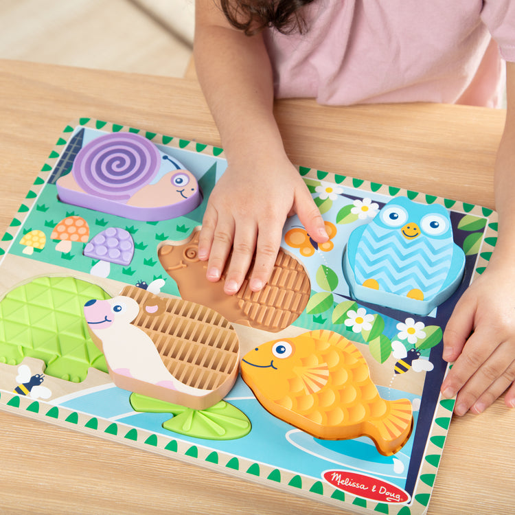 A kid playing with The Forest Friends Touch & Feel Puzzle