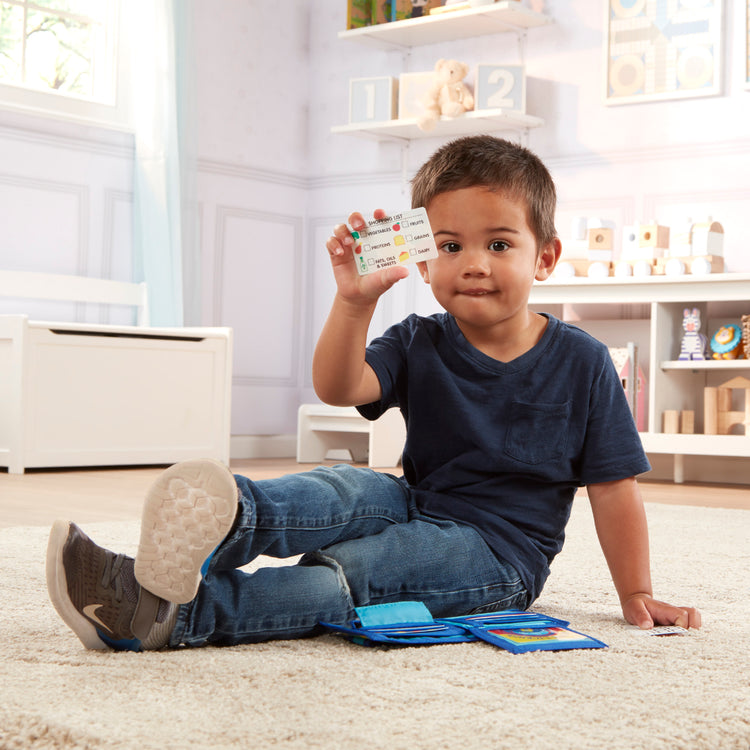 A kid playing with The Melissa & Doug Pretend-to-Spend Toy Wallet With Play Money and Cards (45 pcs), Blue
