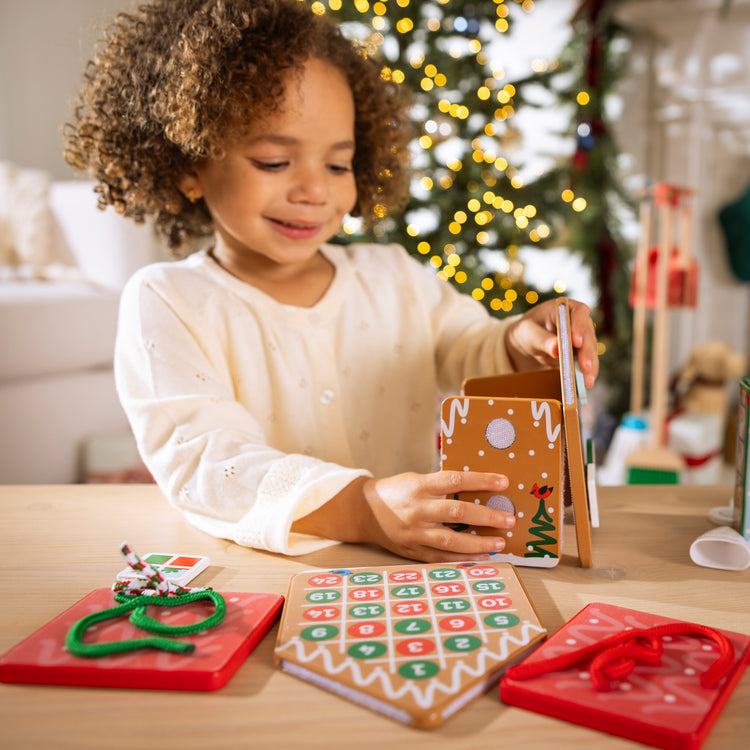 A kid playing with The Melissa & Doug Gingerbread Holiday Post Office, Reusable Build-and-Decorate Pretend Play Set - Ages 3+
