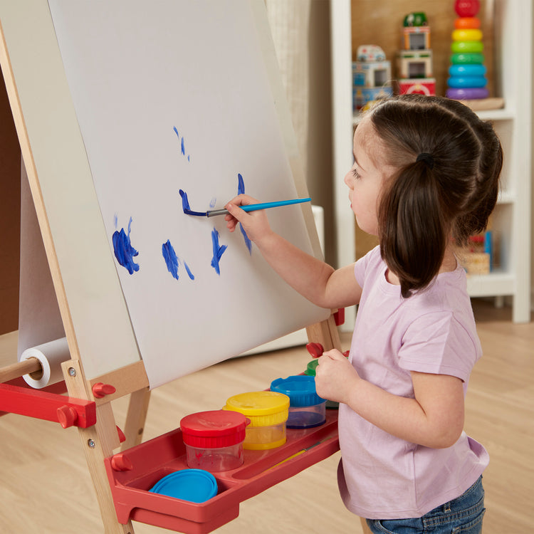 A kid playing with The Melissa & Doug Easel Paper Roll - 17 Inches Wide, 75 Feet Long for Painting, Drawing, Art and Craft Projects for Kids