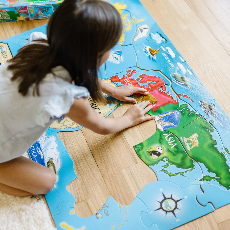 A kid playing with The Melissa & Doug World Map Jumbo Jigsaw Floor Puzzle (33 pcs, 2 x 3 feet)