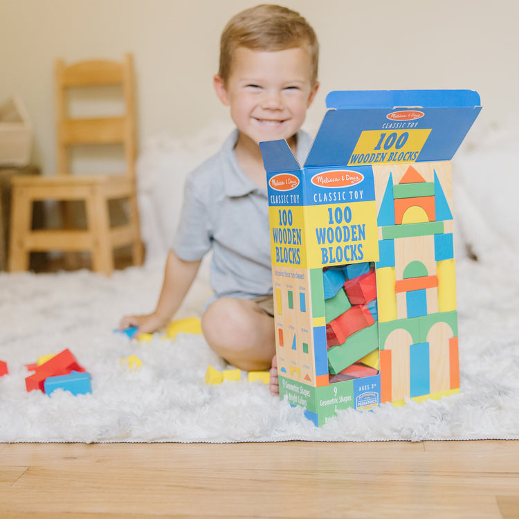 A kid playing with The Melissa & Doug Wooden Building Blocks Set - 100 Blocks in 4 Colors and 9 Shapes