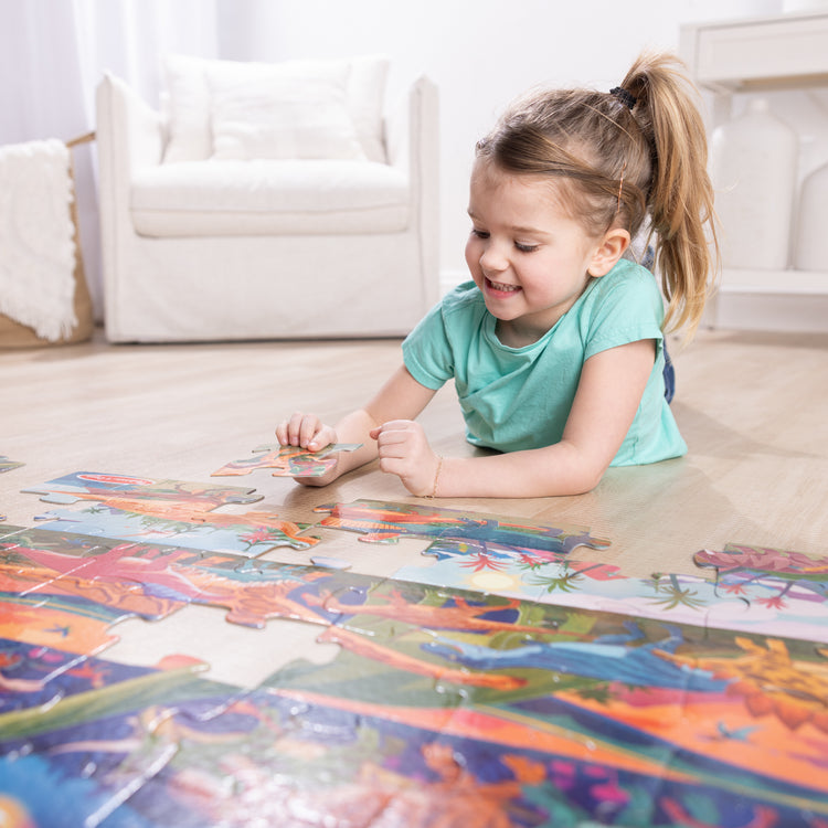 A kid playing with The Melissa & Doug Dinosaurs Jumbo Floor Puzzle, 48-Piece Prehistoric-Themed Jigsaw Puzzle with Dinosaurs and Illustrated Guide, 3 x 2 Foot Kids Puzzles for Toddlers Ages 3+