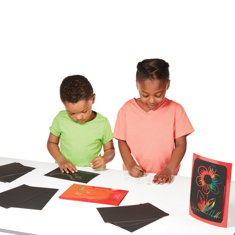 A child on white background with The Melissa & Doug Deluxe Combo Scratch Art Set: 16 Boards, 2 Stylus Tools, 3 Frames