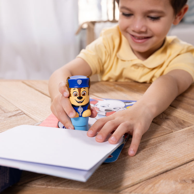 A kid playing with The Melissa & Doug Sticker WOW!™ PAW Patrol Chase Bundle: 24-Page Activity Pad, Sticker Stamper, 500 Stickers, Mini Pad, Arts and Crafts Fidget Toy Collectible Character