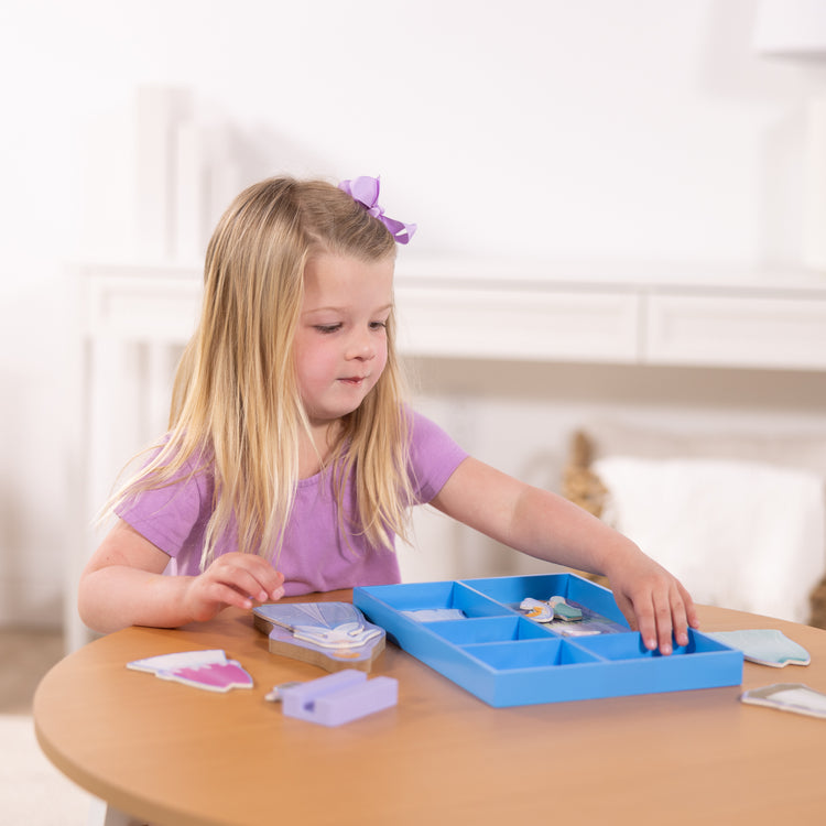 A kid playing with The Melissa & Doug Disney Princess Cinderella Magnetic Dress-Up Wooden Doll Pretend Play Set (30+ pcs)