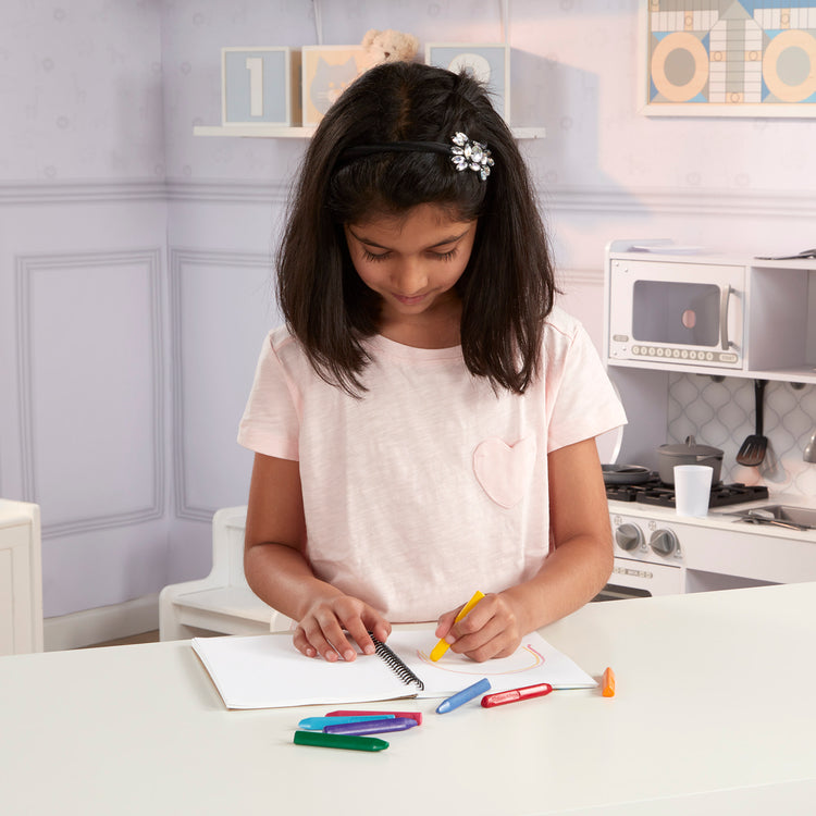 A kid playing with The Melissa & Doug Mini-Sketch Spiral-Bound Pad (6 x 9 inches) - 4-Pack