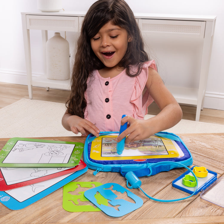 A kid playing with The Melissa & Doug Water WOW! Water WOW! Take-Along Multi-Activity Color-Reveal Drawing Set Travel Toy Ages 3+