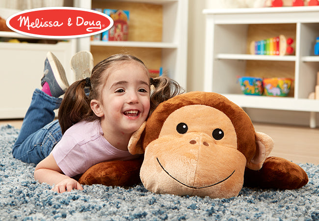 A kid playing with The Melissa & Doug Cuddle Monkey Jumbo Plush Stuffed Animal with Activity Card