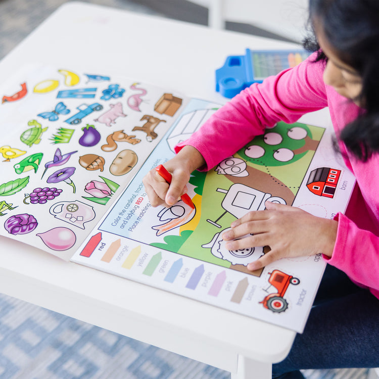 A kid playing with The Melissa & Doug Colors and Shapes Coloring and Sticker Activity Pad