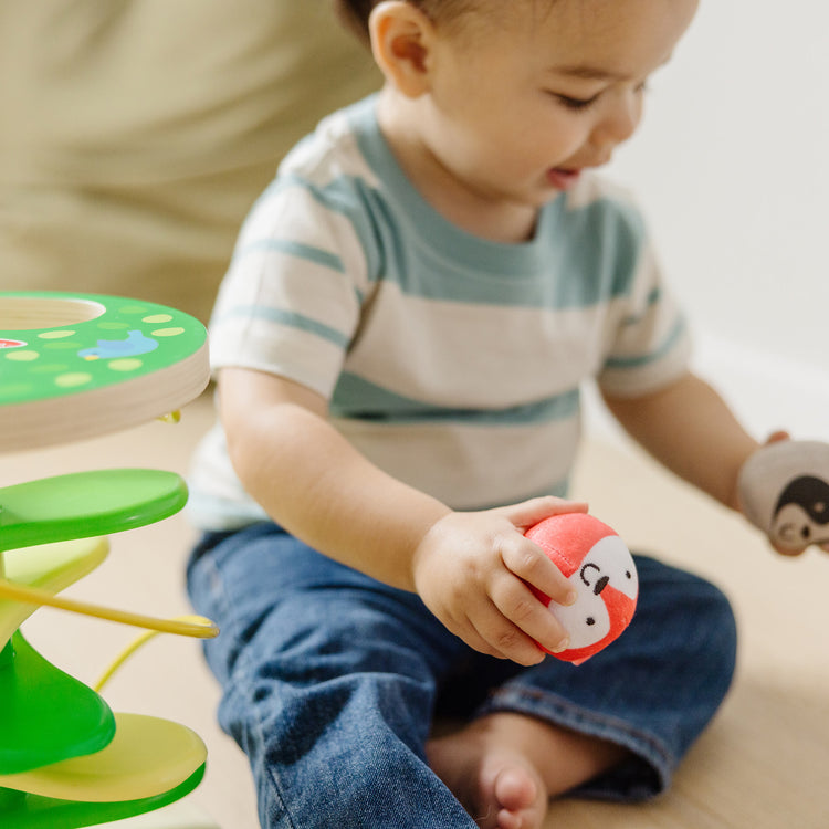 A kid playing with The Melissa & Doug Rollables Treehouse Twirl Infant and Toddler Toy (3 Pieces)